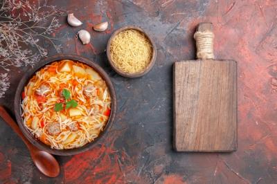 Delicious Chicken Noodle Soup in a Bowl with Garlic on Cutting Board – Free Download