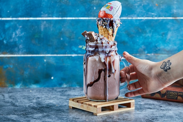 A Woman’s Hand with Tattoo Holding a Mug of Chocolate Smoothie on a Blue Surface – Free Stock Photo, Download Free