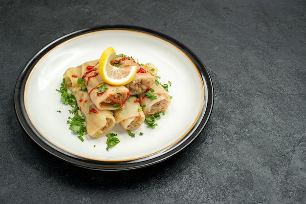 Stuffed Cabbage Close-Up with Herbs, Lemon, and Sauce on Black Table – Free Stock Photo, Download for Free