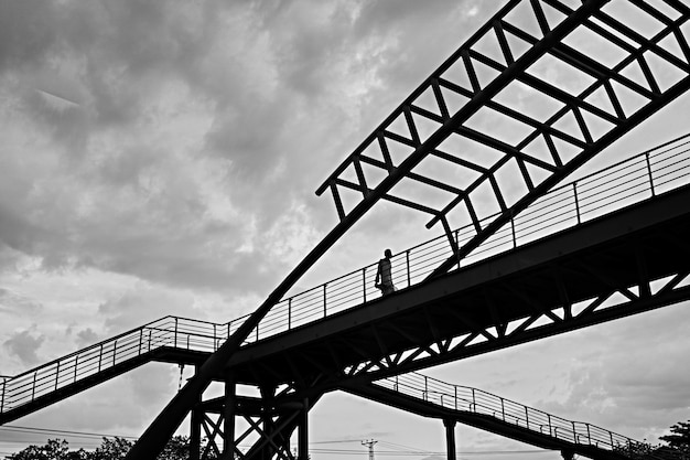 Low Angle Greyscale Shot of a Male Walking Through a Bridge – Free Download