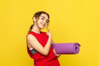 Young Woman Smiling Against a Yellow Wall with a Purple Carpet – Free Stock Photo Download