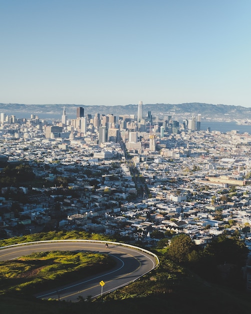 Curvy Road Downhill with Cityscape Under Blue Sky – Free Download