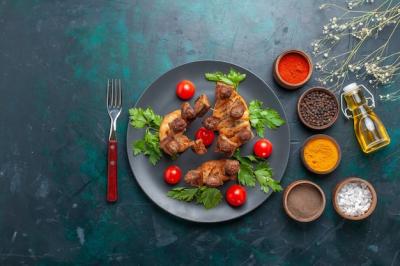 Top View of Sliced Cooked Meat with Cherry Tomatoes and Seasonings on Blue Background – Free Stock Photo, Download for Free