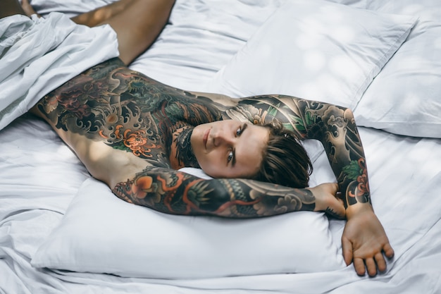 Colorful Tattooed Man Posing on White Sheet – Free Download