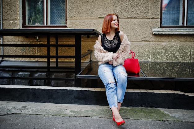 Red haired girl with red handbag in city street – free download