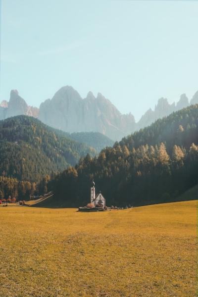 Stunning Vertical View of a Beautiful Building in a Dry Grassy Field with Forested Mountains – Free Download