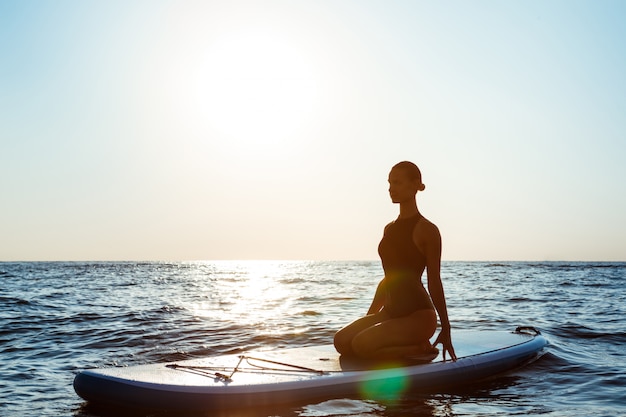 Beautiful Woman Practicing Yoga on Surfboard at Sunrise – Free Download