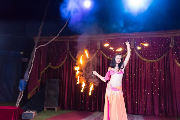 Exotic Dark Haired Fire Dancer in Bright Costume Twirling Flaming Baton on Stage â Free Download