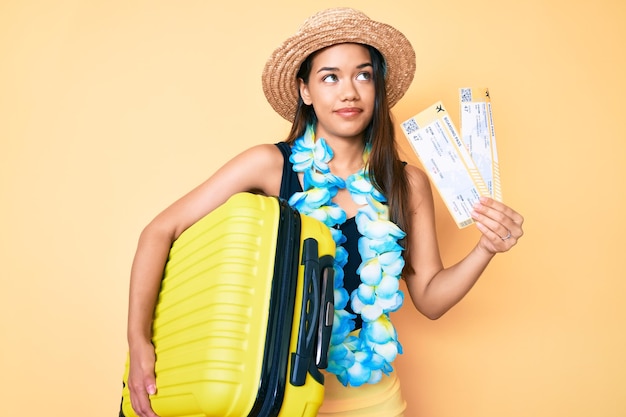 Young Beautiful Latin Girl with Summer Hat and Hawaiian Lei Holding Cabin Bag and Boarding Pass – Download Free Stock Photo