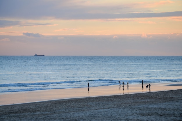 Stunning Beach Sunset with People Under a Cloudy Sky – Free to Download