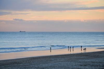 Stunning Beach Sunset with People Under a Cloudy Sky – Free to Download