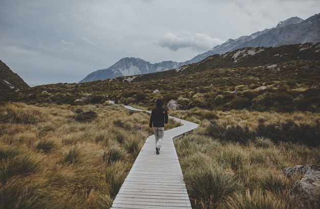 Stunning View of Mount Cook in New Zealand with a Man Walking in Hooker Valley – Free Download