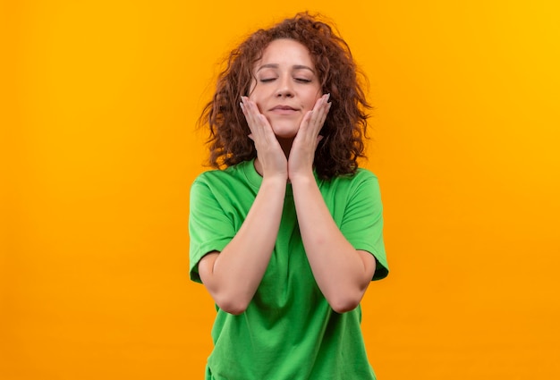 Young Woman with Short Curly Hair Expressing Positive Emotions Against an Orange Wall – Free Stock Photo, Download Free