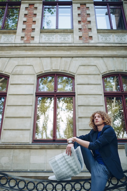 Young Reddish Man Reading Newspaper Near Old Style Building – Free Download