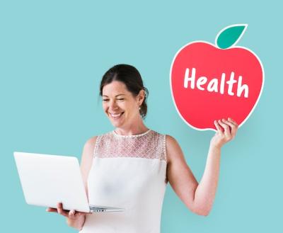 Woman Holding a Health Icon While Using a Laptop – Free Download