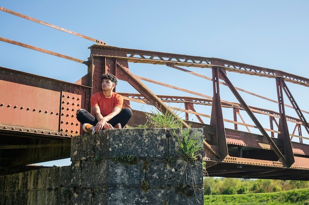 Young Lonely Male Hiker Sitting Near Bridge – Free Stock Photo for Download