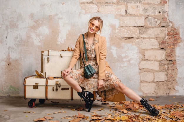 Blonde Woman in Beige Coat Sitting on Suitcases Against Wall in Street – Free Stock Photo, Download Free