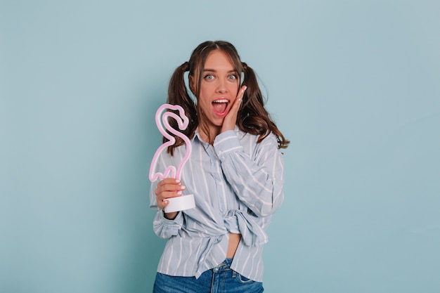 Charming Girl in Blue Shirt Smiling with Pink Flamingo – Free Stock Photo for Download