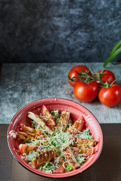 A Red Plate with Caesar Salad and Tomatoes on a Marble Surface – Free Stock Photo for Download