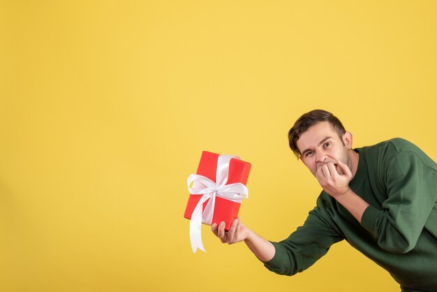 Handsome Young Man Holding Gift on Yellow Background – Free Download