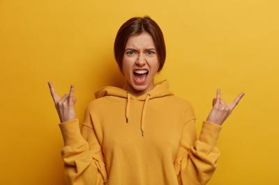 Irritated Carefree Young Woman Expressing Excitement with Rock n Roll Gesture – Free Download