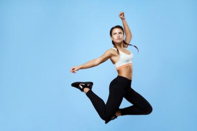 Excited Fitness Woman in Colorful Sportswear Jumping High – Free Download