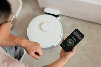 High Angle View of a Man Using a Robotic Vacuum Cleaner at Home – Free Download