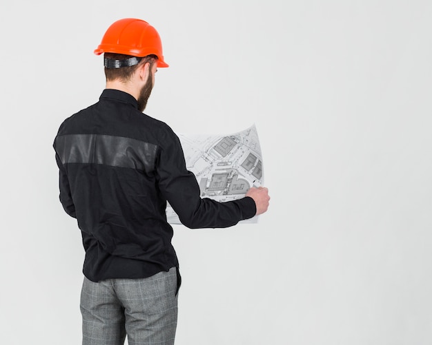 Male Architect Reviewing Blueprint Against White Background – Free Stock Photo for Download