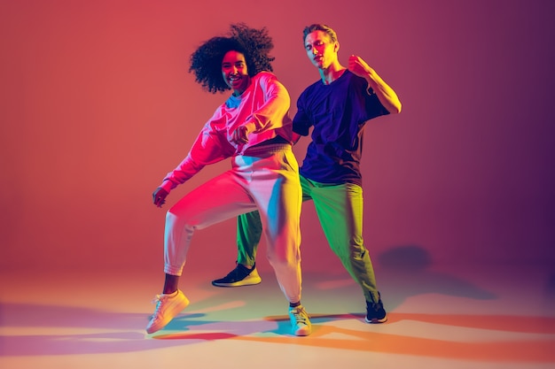 Stylish Men and Women Dancing Hip-Hop in Bright Clothes on a Neon Green Background – Free Download