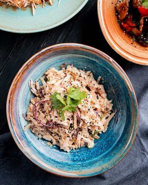 Delicious Top View of Salad with Chopped Cabbage, Chicken, and Black Seeds on Wooden Surface – Free Download