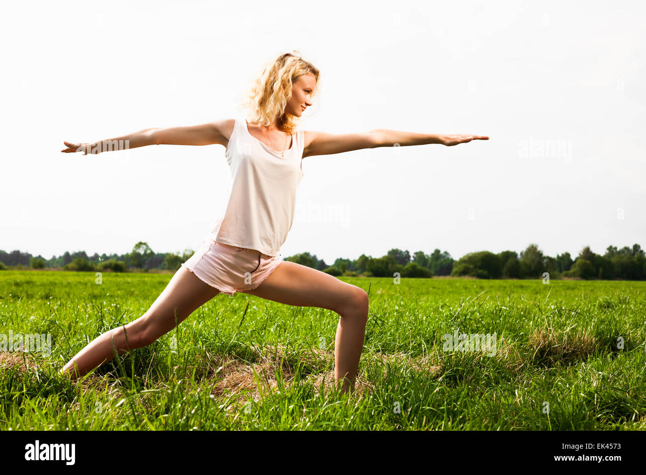 Beautiful young woman doing yoga exercise on field Stock Photo Alamy